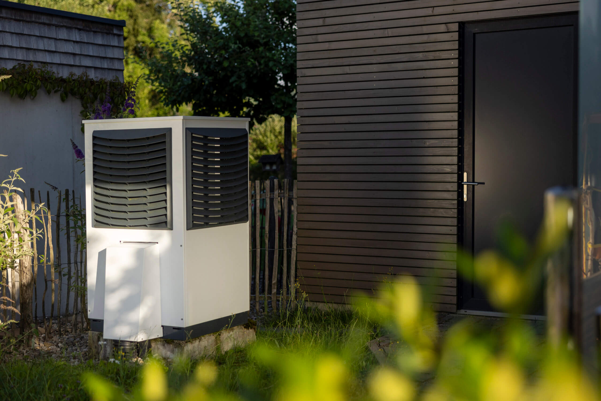 Wärmepumpe im Garten vor einem Haus